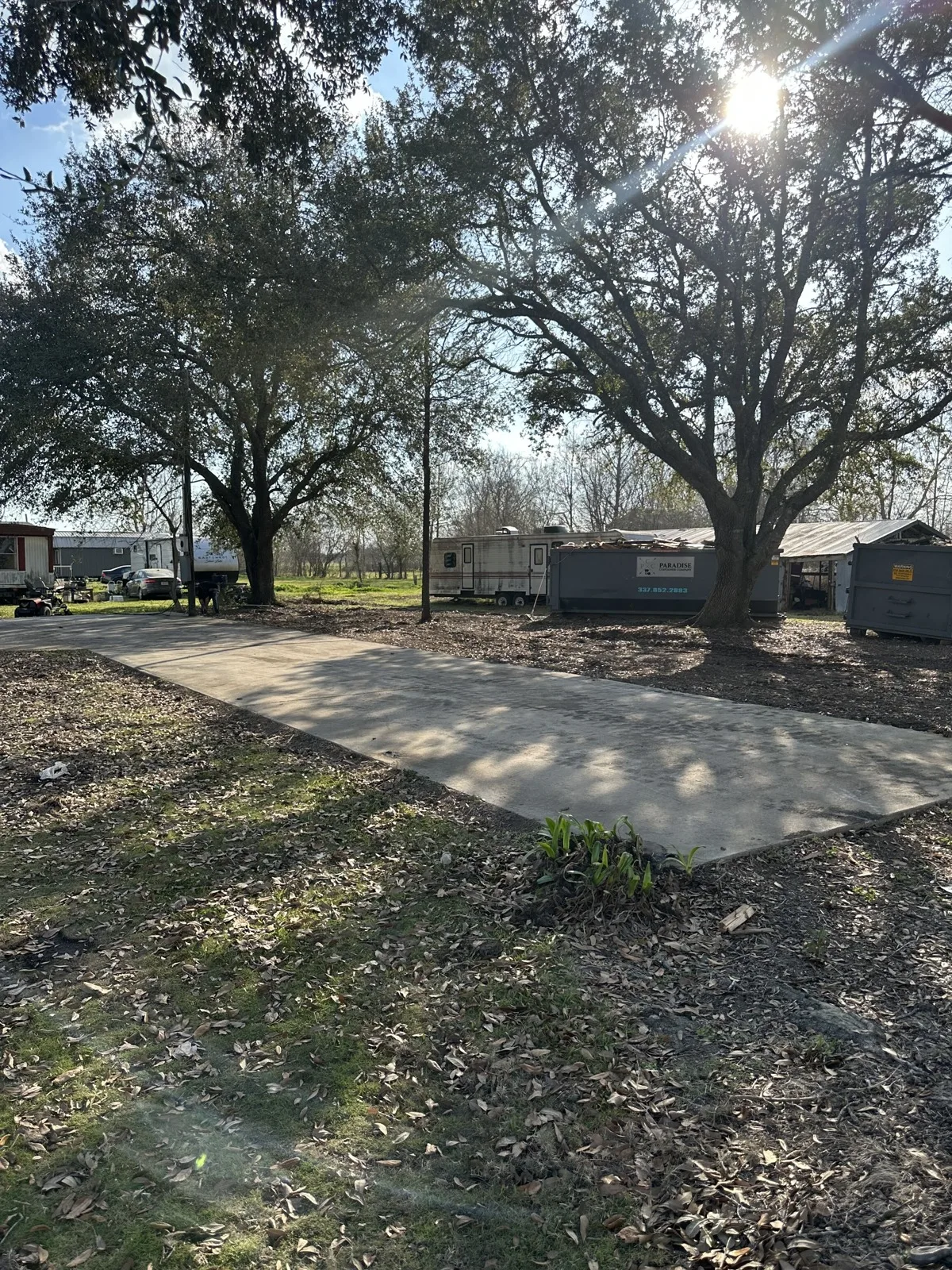 Cleared lot with the slab exposed and a roll-off container after a house demolition